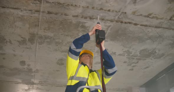 Construction Worker Drilling Hole on Ceiling with Electrical Drilling Machine