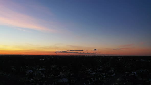 An aerial shot over a suburban neighborhood during a golden sunrise. The camera dolly in to the hori