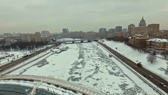 Flying Over the Frozen Moskva River in Winter Towards the Pedestrian Glass Bridge