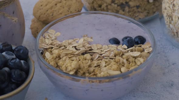 Woman Preparing Healthy Blueberry Smoothie Bowl with Blueberries Chia Seeds and Granola