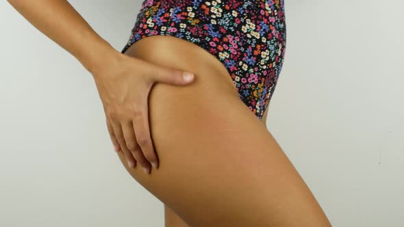 A woman with a perfect body applies a refreshing cream or body lotion to her leg.