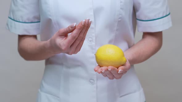 Nutritionist Doctor Healthy Lifestyle Concept - Holding Lemon Fruit and Medicine or Vitamin Pill
