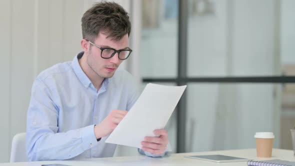 Young Man Reacting to Loss While Reading Documents