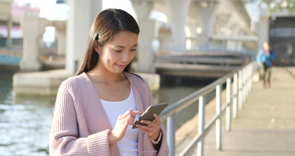 Woman use of mobile phone under sunlight