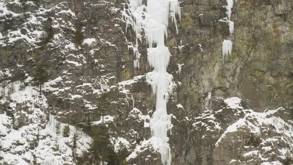 Extreme wide aerial showing climber scaling ice cascade Maineline, Mount Kineo