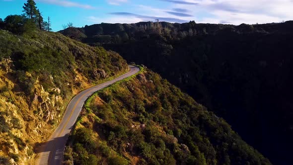 Mountain Road winds along Steep Green Hill at Dawn, Drone Dolly In