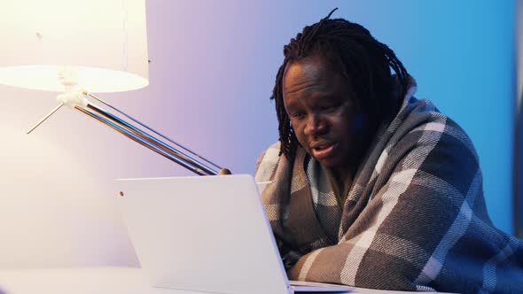 Man with Thermometer Shaking Wrapped in the Blanket Using Laptop to Seek Medical Help