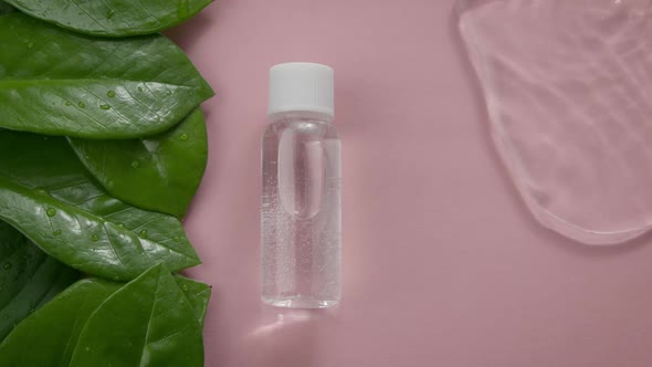 Cosmetic Bottle with Transparent Gel in Water Splash on Pale Pink Background