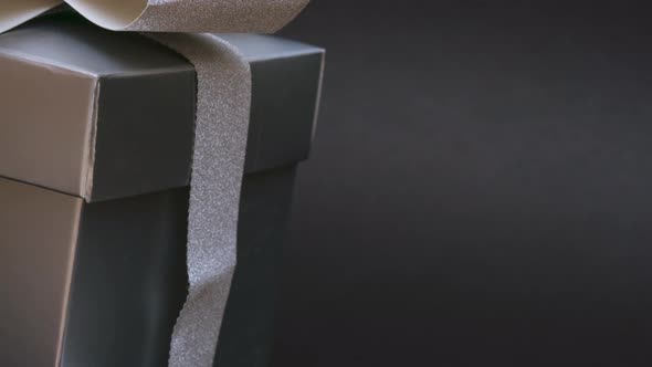 Festive Gray Box with a Gift with a Silver Ribbon and Bow and Christmas Balls