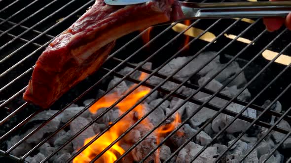 Chef Puts Steak Using Tongs on the Grill Grate