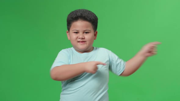 Inspired Asian Little Boy Smile And Pointing To The Side While Standing In The Green Screen