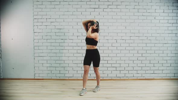 Young Woman with Curly Hair Drives Weight Around Her Head on Workout