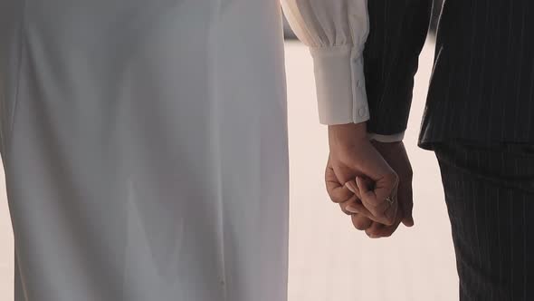 Bride in Vintage Dress and Groom Walk Joining Hands in Park