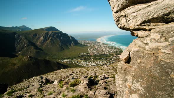 Panning shot from vantage point of mountain and pristine beach along coastline, Hermanus, South Afri