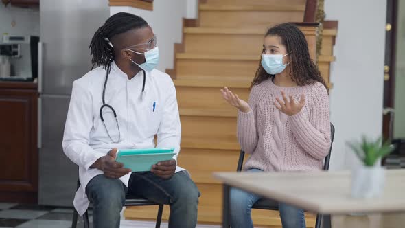 Confident Professional African American Doctor Taking Medical History Visiting Ill Teen Girl at Home