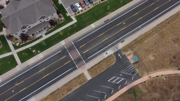 A high drone shot drops and zooms on a man walking his dog near a park.