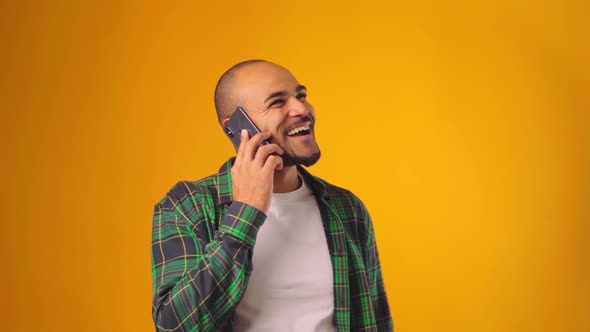 Young African American Man Talking on the Phone Against Yellow Background