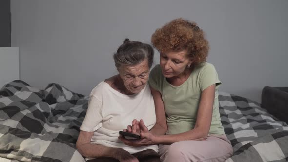 Elderly Daughter Teaching Her Senior Mother To Use Mobile Phone