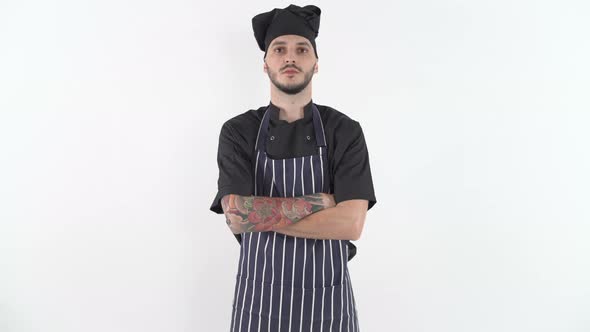 Serious Tattooed Chef in Uniform with His Arms Crossed Looking at Camera