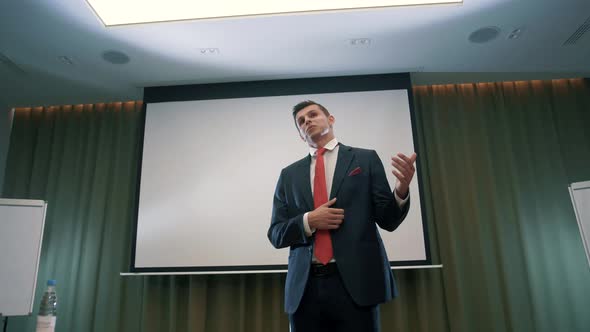 Successful male speaker in a classic suit gives a lecture on increasing