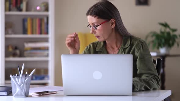 Beautiful Elderly Woman is Working with Laptop at Table in House During Selfisolation Spbi