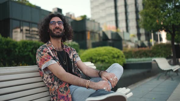 Relaxed curly-haired bearded man in eyeglasses looking around