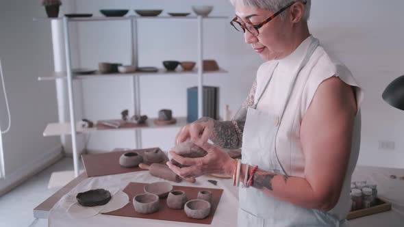 Asian elderly woman enjoying pottery work at home.