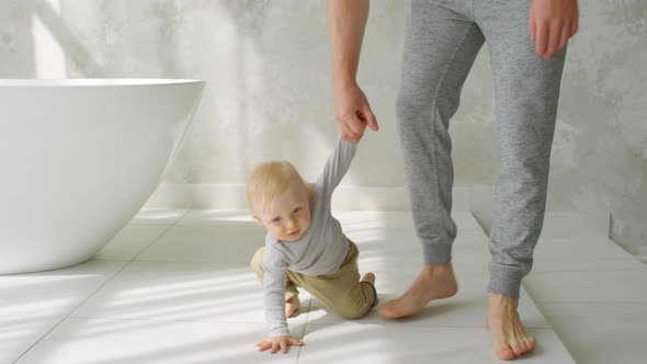 Father Trying to Teach Baby to Walk in Bathroom