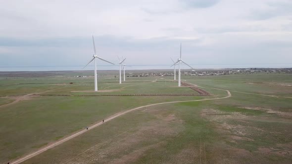 A Group of Cyclists Rides Along the Windmills