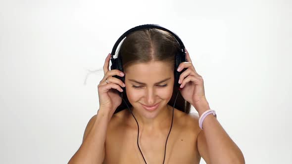 Beautiful Female in Headphones Listening To the Music with Fluttering on the Wind Hair Over White