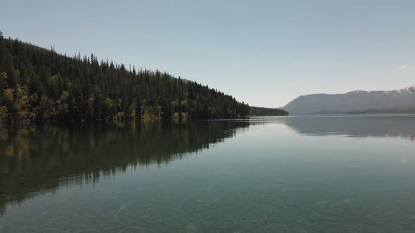 cinematic Lake Mcdonald flying low on top of the lake, national forest and mountains