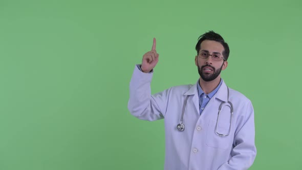 Stressed Young Bearded Persian Man Doctor Pointing Up