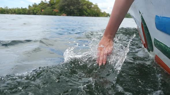 Female Arm Touches Water Surface Relaxing on the Deck of Boat. Hand of Young Woman Moves Through Sea