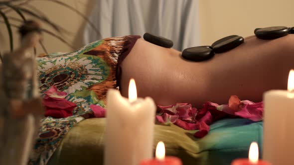 Young Woman Getting Hot Stone Massage at Spa Salon, Close Up of Hot Stones on Back