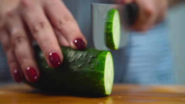 Women cuts a cucumber with a knife