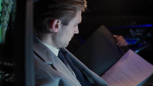 Young Businessman Sitting in a Moving Car and Reads Paper Documents Man Top Manager in a Suit is