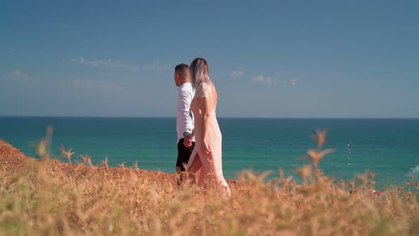 A Young Couple Walks Along the Seashore at a Romantic Meeting