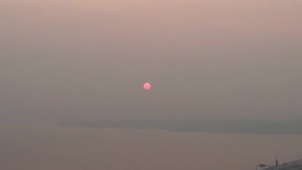 Slow aerial zoom out of the sunrise blanketed by thick wildfire smoke over Lake Washigton