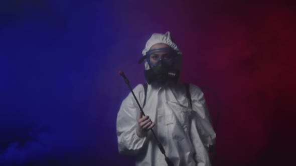 A Person in White Protective Medicine Suit Walks in Smoky Room Holding Cleaning Equipment and