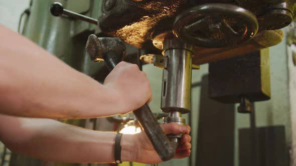 Caucasian male hands factory worker at a factory standing at a workbench and operating machinery