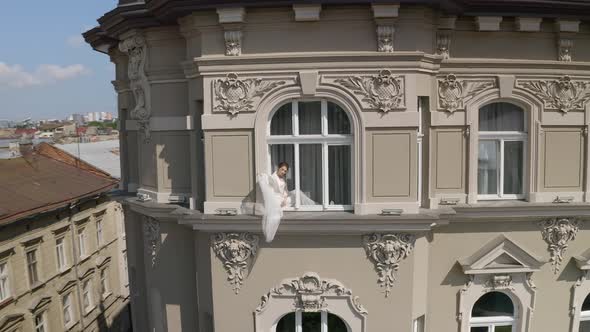 Bride in Boudoir Dress Sitting on Window Sill Wedding Morning Preparations Woman in Night Gown Veil