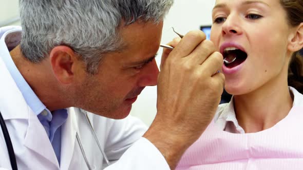 Dentist examining a female patient with tools