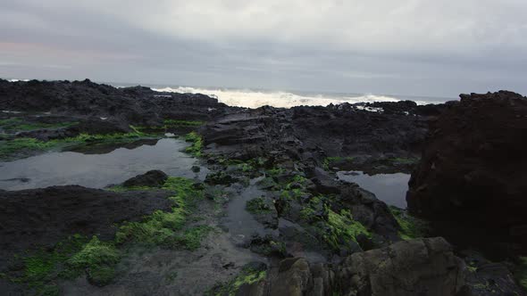 Panning motion over rocky beach as waves crash on shore.