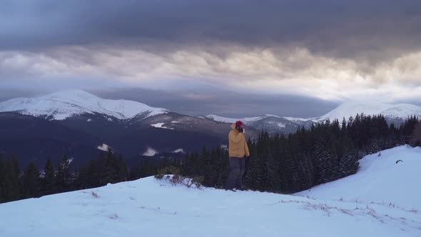 A Traveler Talks on the Phone in the Mountains in Winter