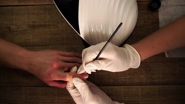 Nail Master is Painting Art Design to Male Client By Brush During Beauty Procedure Filmed From Above