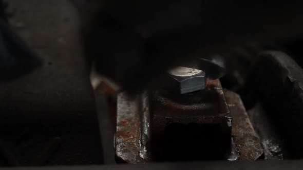 a Worker Tightens a Large Bolt with a Large Wrench