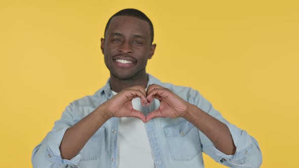 Young African Man Heart Sign By Hand Yellow Background