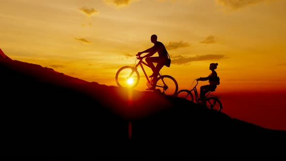 Young Bicycle Climbing Mountain at Sunset alt