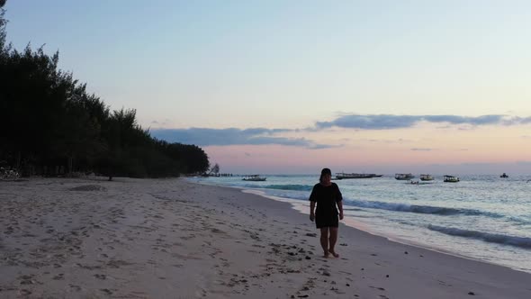 Single female posing on tropical seashore beach holiday by aqua blue lagoon and white sandy backgrou