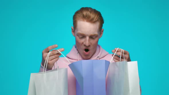 Happy Redhead Man Standing in Studio with Shopping Bags